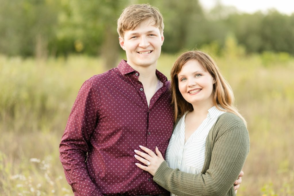 couple smiling at the camera in tall grass in Eau Claire