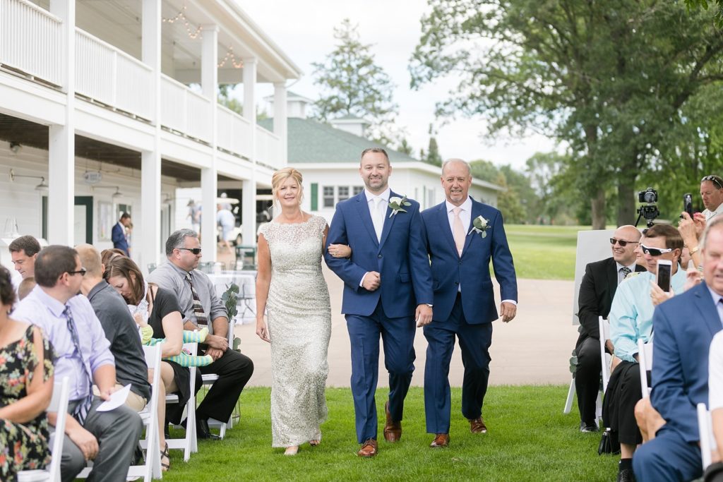 groom walking down the aisle with his mom and dad at Lake Wissota Golf & Events