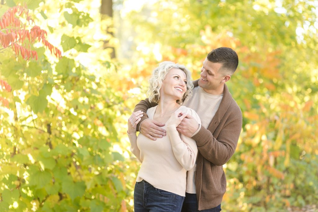 couple with gold trees behind them for their fall engagement session in Minneapolis at St. Anthony Main
