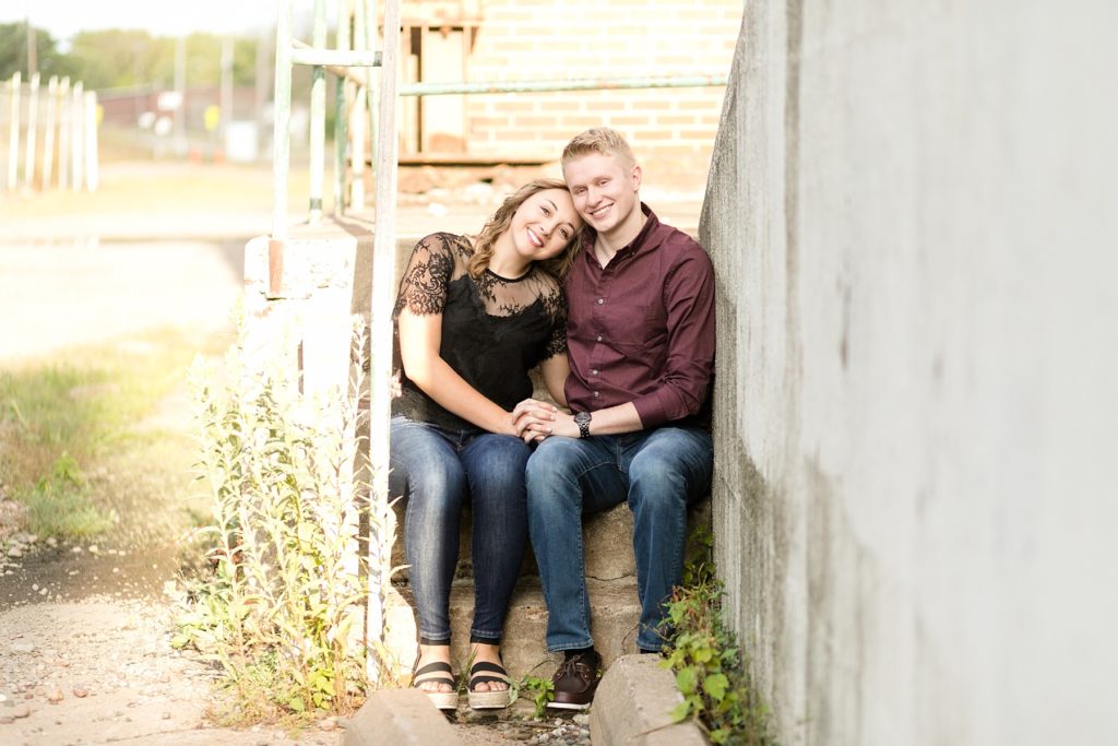 couple cuddled on some abandoned stairs in Eau Claire for their engagement photos