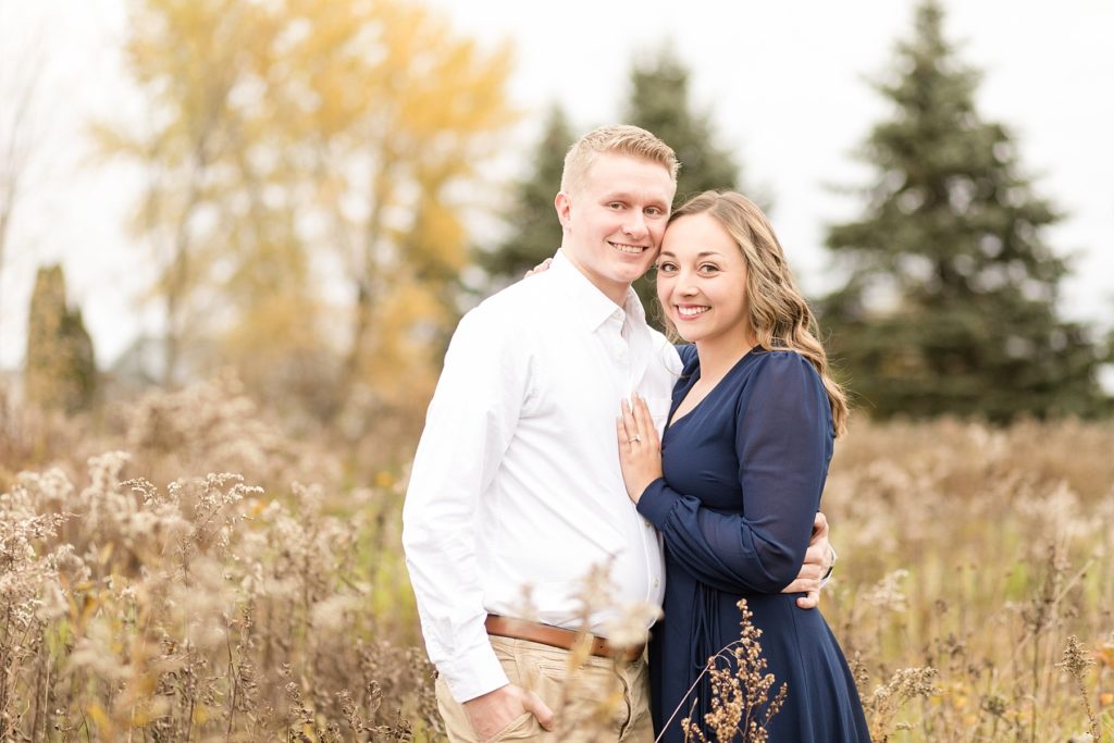 couple in a field for their woodsy Wisconsin engagement session