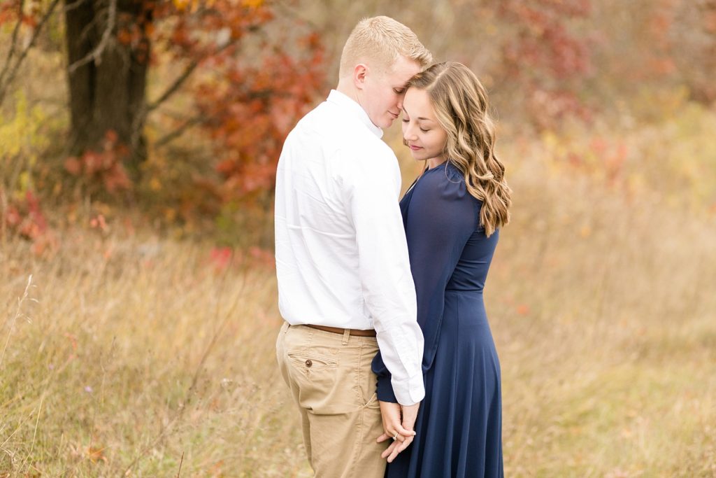 couple cuddling in the fall for their woodsy Wisconsin engagement session