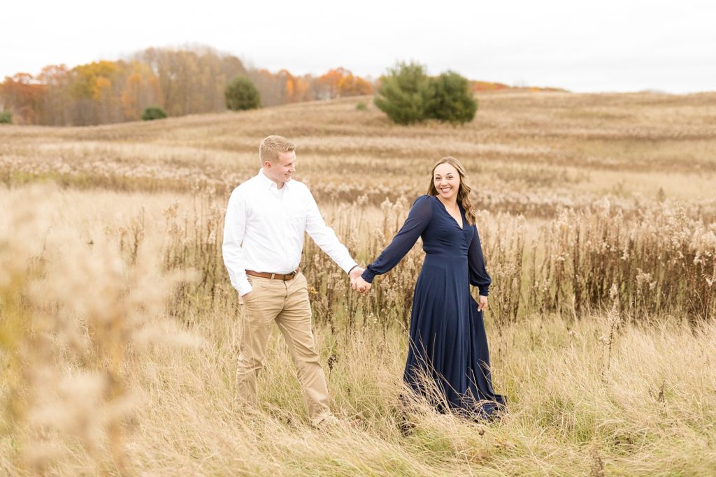 couple walking through a field near the Ice Age Trail for their woodsy Wisconsin engagement session