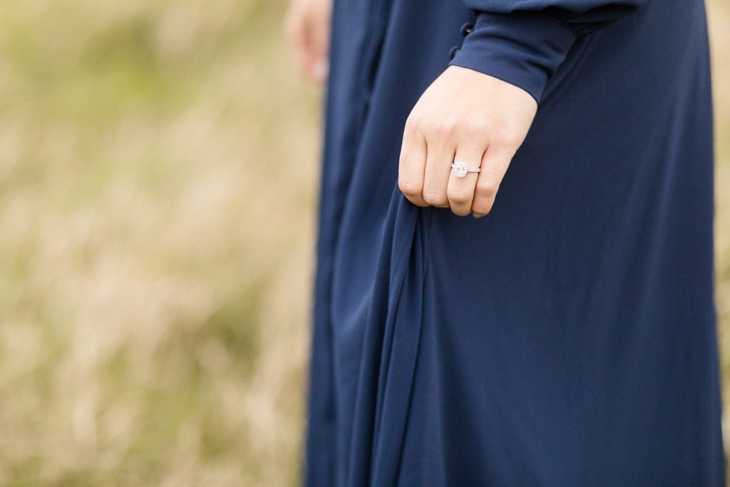 bride with engagement ring in a dark blue dress from Lulus near the Ice Age Trail for their woodsy Wisconsin engagement session