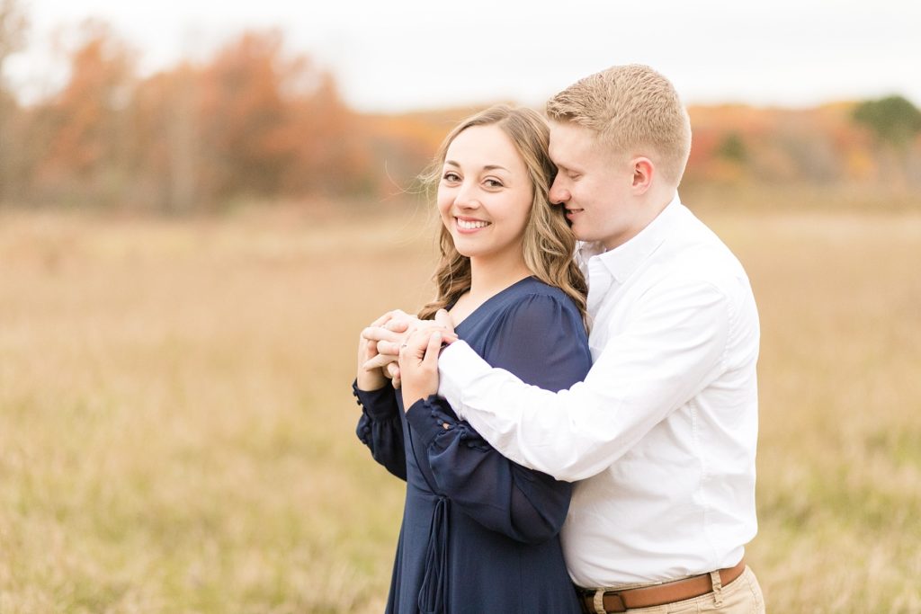 couple in a field for their woodsy Wisconsin engagement session