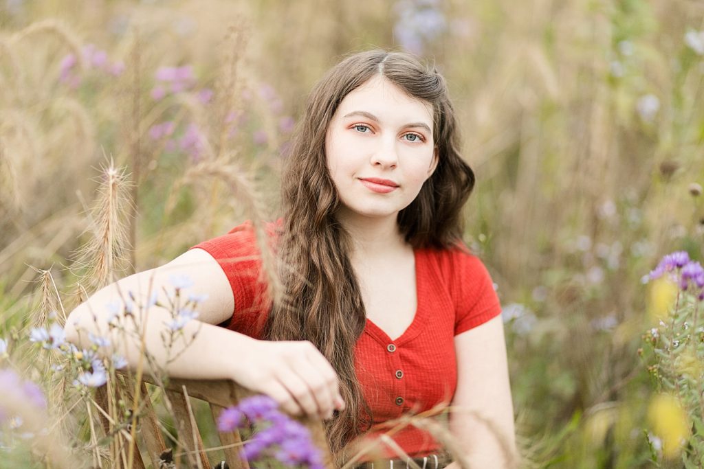 girl sits in field of flowers for her Cadott High School senior photos