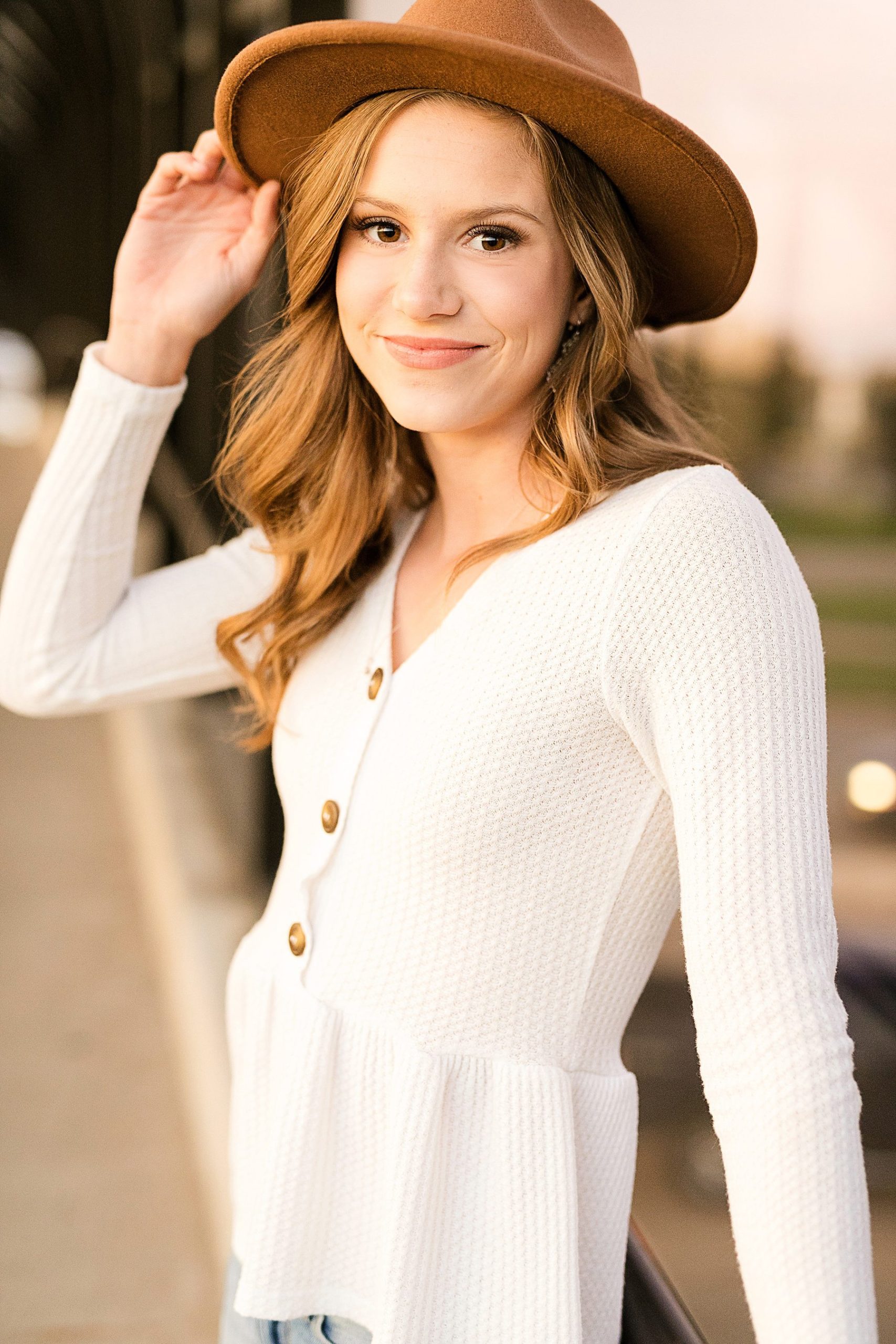 Senior girl with hat on smiling at camera in Eau Claire WI for her boho senior photos.