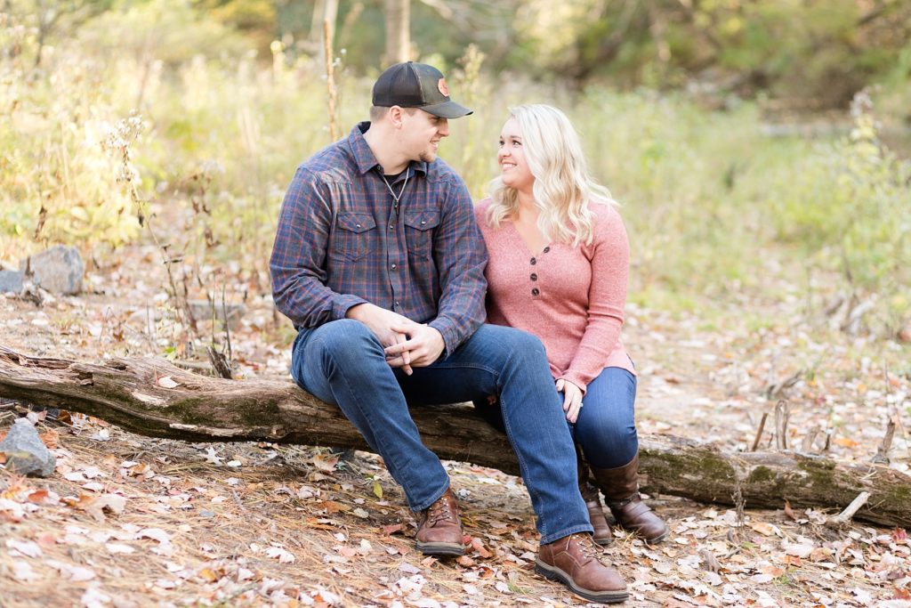 couple sitting on a downed log at Erickson Park in Chippewa Falls for their engagement session