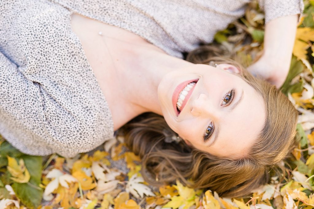 girl laying in the leaves for her fall Eau Claire senior photos