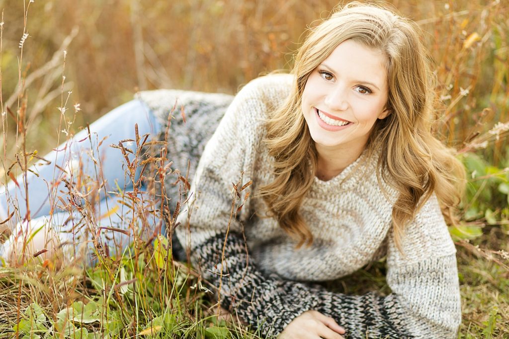girl laying in a field for her fall Eau Claire senior photos at River Prairie