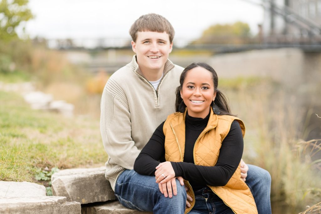 couple sitting on stones at Phoenix Park in Eau Claire for their engagement photos