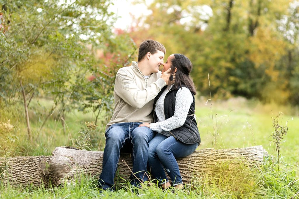 couple sitting on a log at River Prairie in Eau Claire for their engagement photos