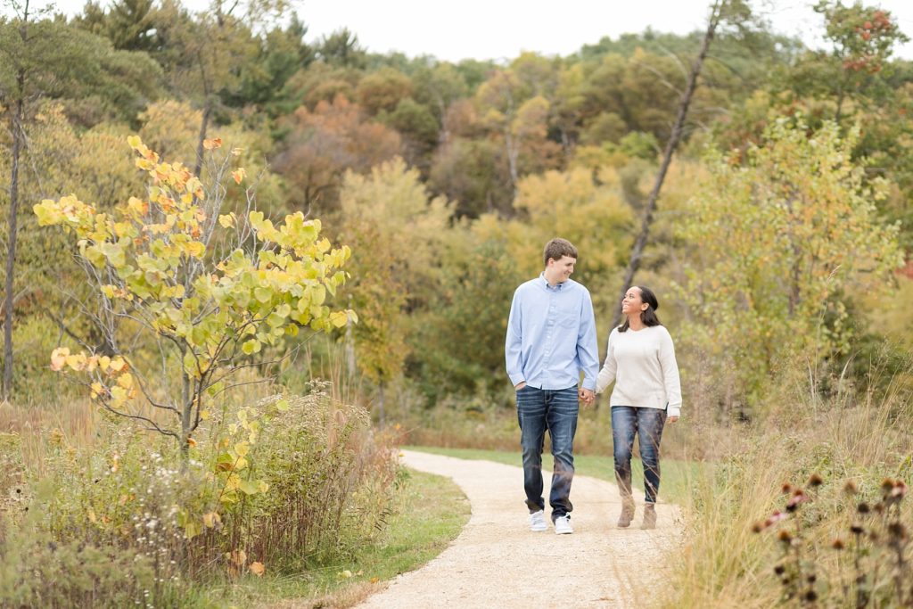 couple walking through the grass at River Prairie in Eau Claire for their engagement photos