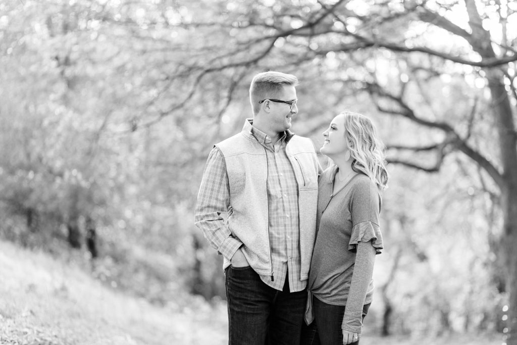 couple in a black and white photo smiling at each other in the late fall in Chippewa Falls for their engagement photos