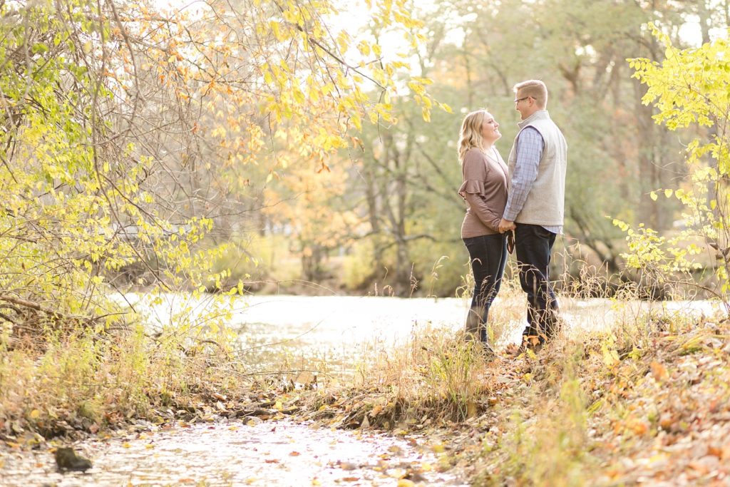 couple standing on a small peninsula for their late fall Irvine Park engagement photos in Chippewa Falls