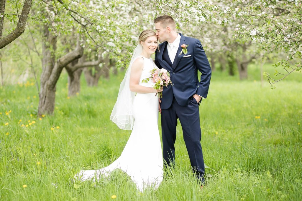 couple tucked in blossoming trees kissing on their wedding day in Rice Lake, WI