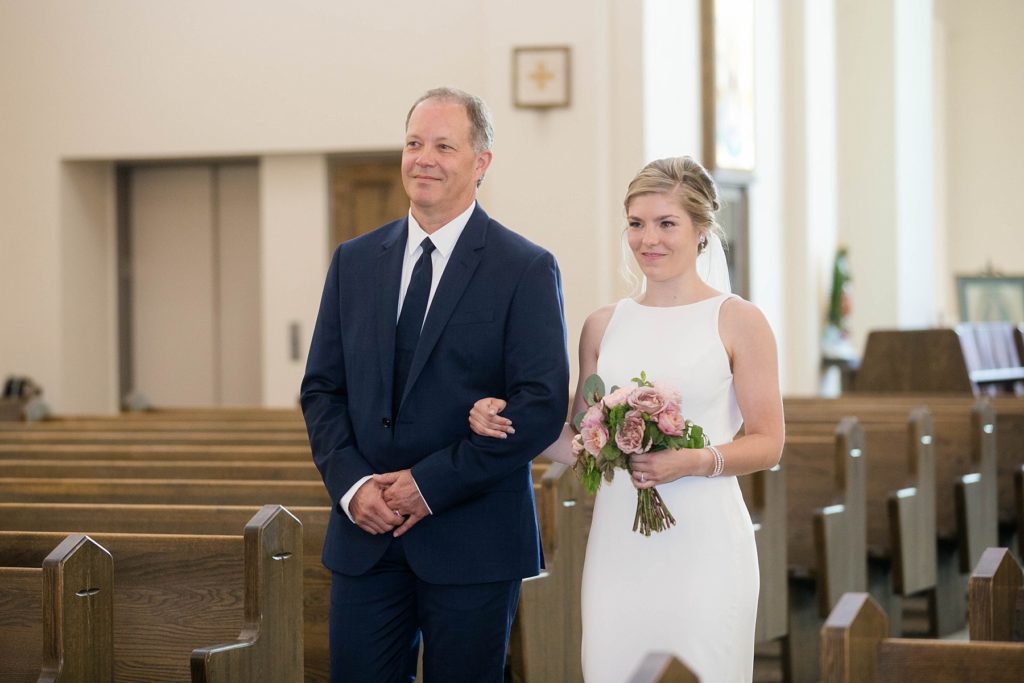 bride walking down the aisle with her father at her wedding at St. Joseph Catholic Church in Rice Lake,. WI