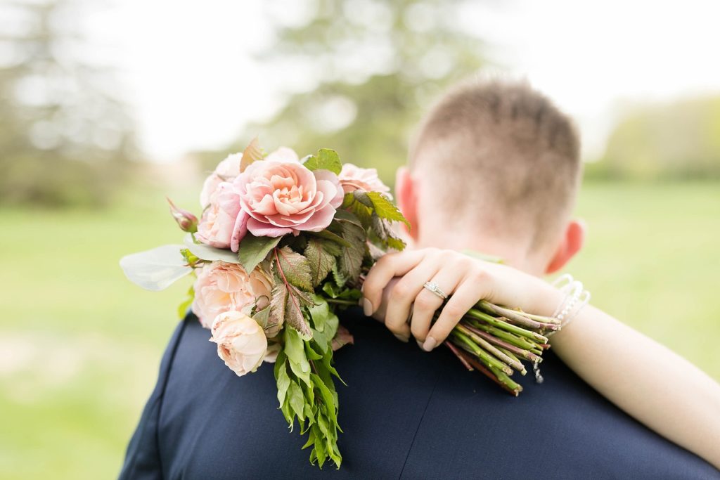 bouquet over grooms shoulder in brides hand in Rice Lake, WI at Turtleback Golf