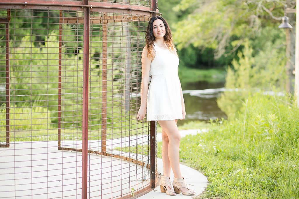 girl in a white dress leaning on a corn crib  for her Eau Claire senior photos