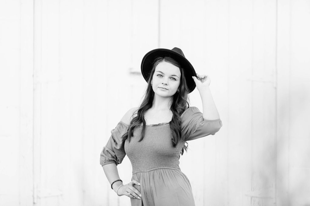 girl in a black and white photo holding onto a black hat  for her boho senior session in Eau Claire, WI