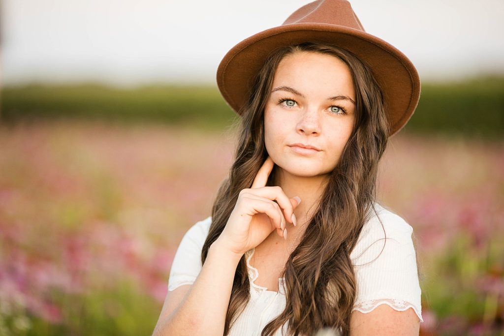 girl with a brown hat on in a field of wildflowers for her boho senior session in Eau Claire, WI