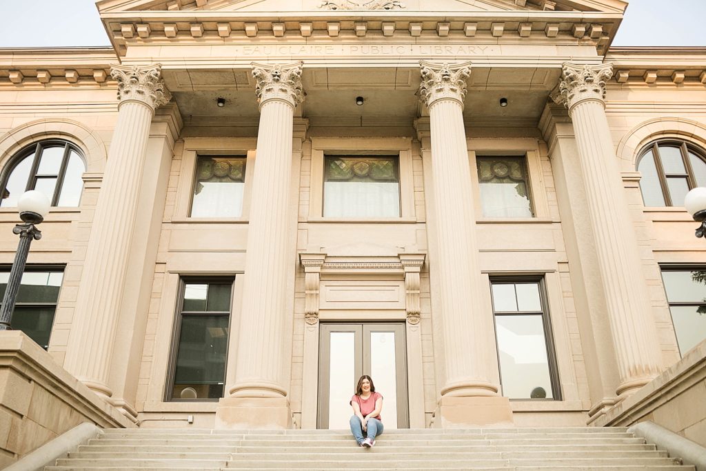 girl sitting on the staircase of the Eau Claire courthouse in Eau Claire for her laid back senior photos