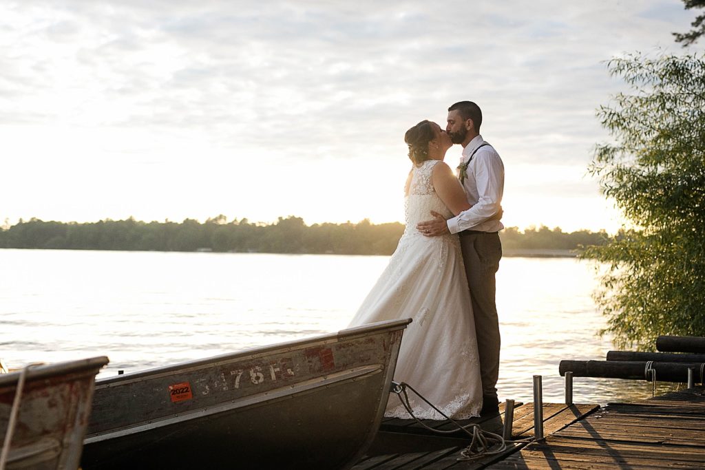 couple kissing on the dock on Lake Chetek at sunset on their wedding day
