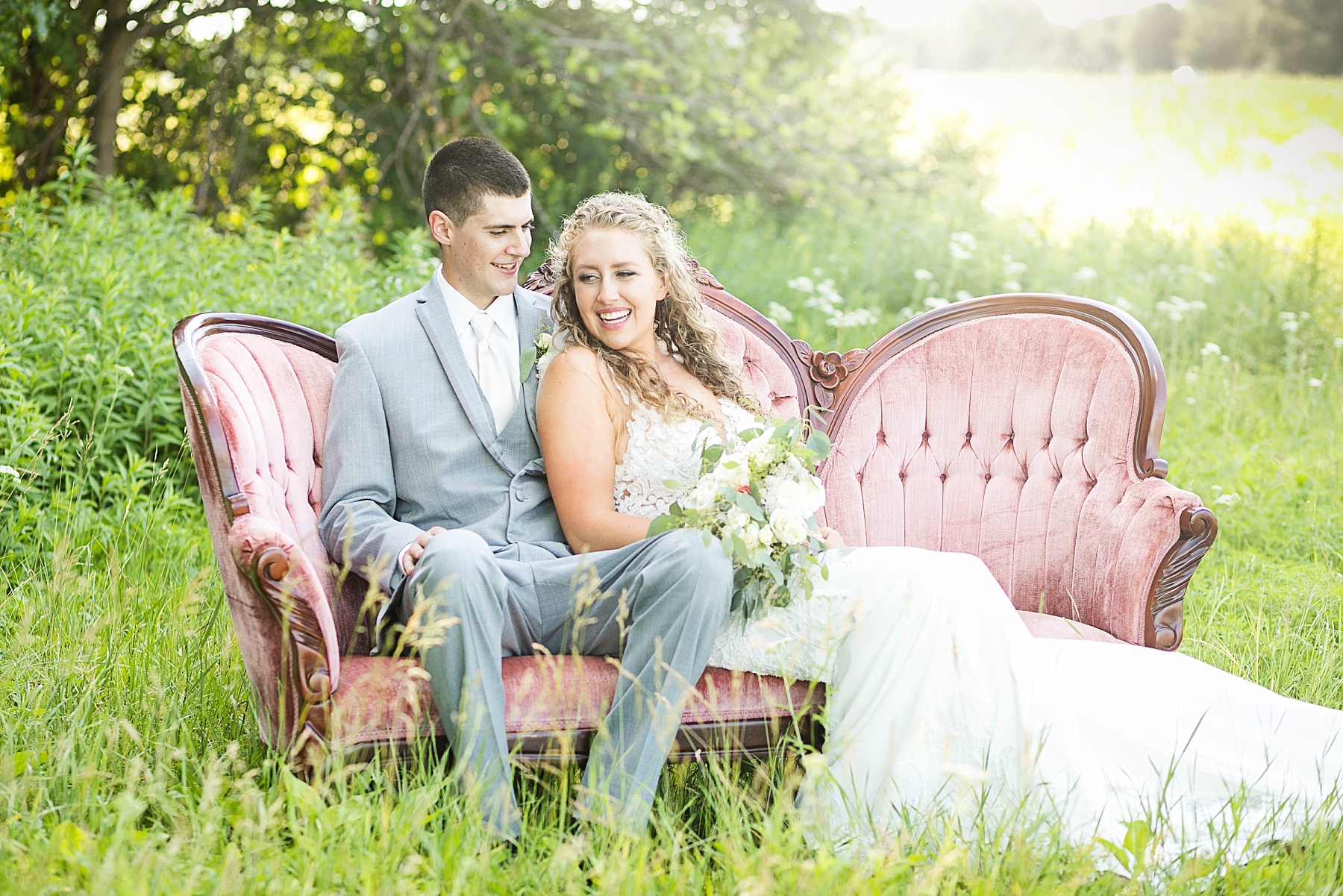 couple sitting on a rented couch from Sweet Legacy in Eau Claire at their summer wedding at The Florian Gardens