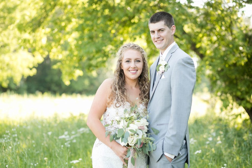 couple smiling at the camera in a field at The Florian Gardens in Eau Claire WI
