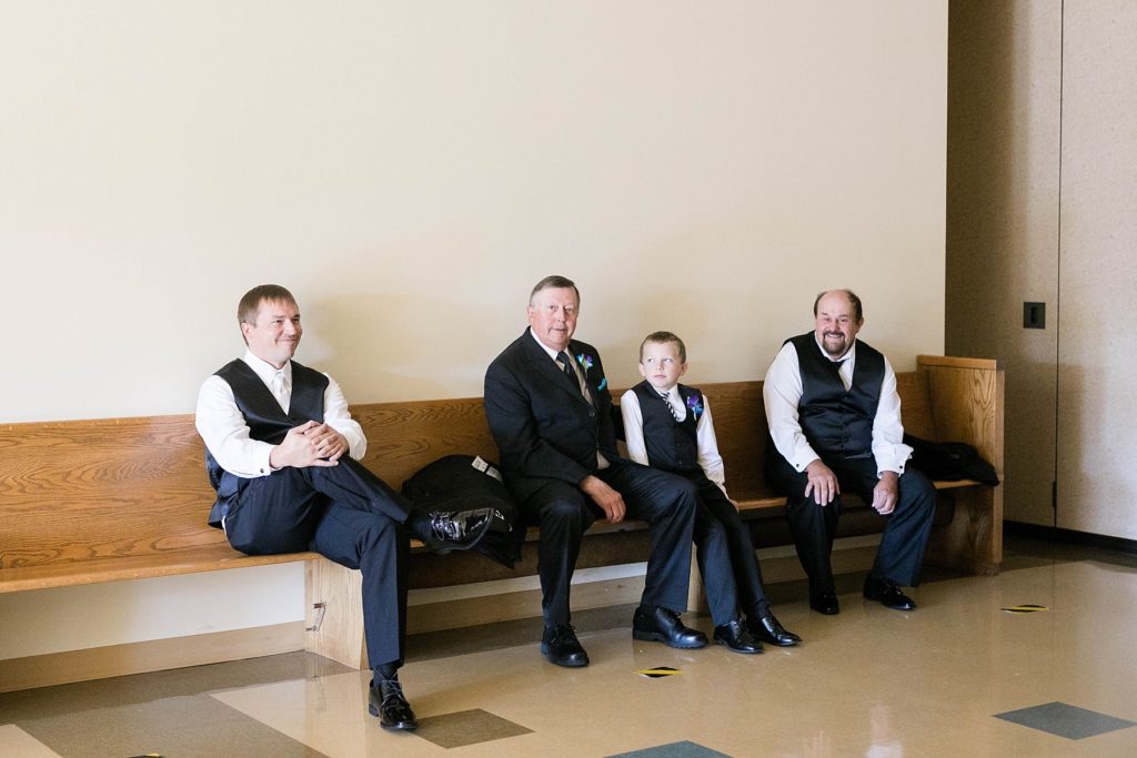 groom and fathers sitting and waiting for the ceremony to start at Immaculate Conception Church in Eau Claire