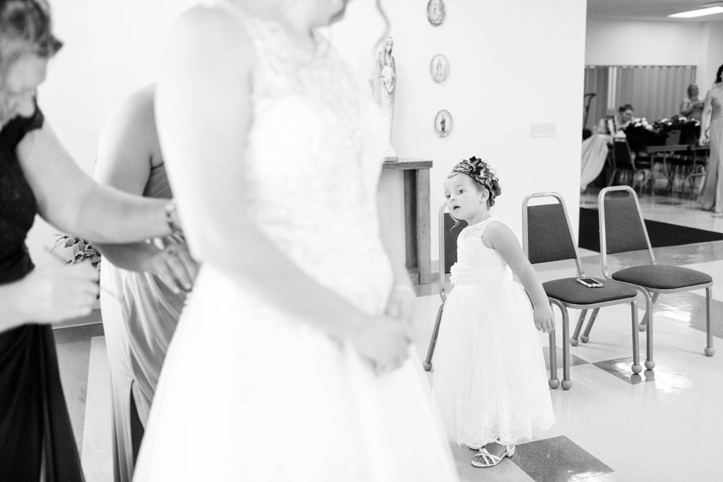 flower girl looking at the bride getting into her gown at Immaculate Conception Church in Eau Claire