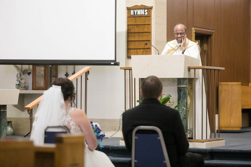 priest smiling at the couple during the homily at Immaculate Conception Church in Eau Claire