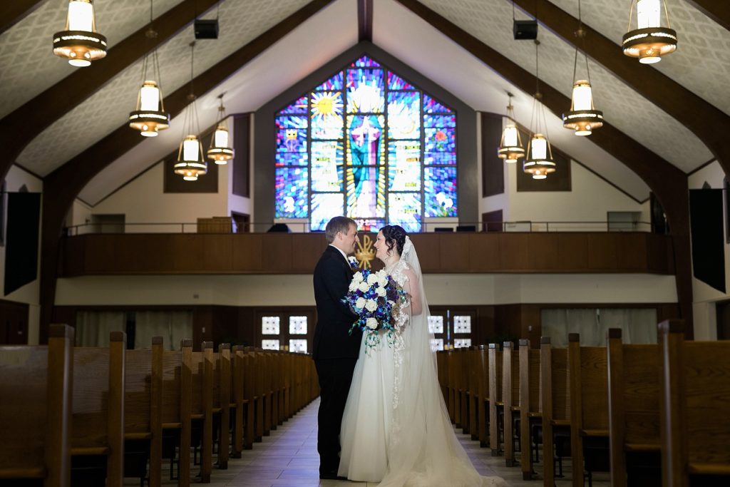 low light portrait of the bride and groom in an empty sanctuary at Immaculate Conception Church in Eau Claire
