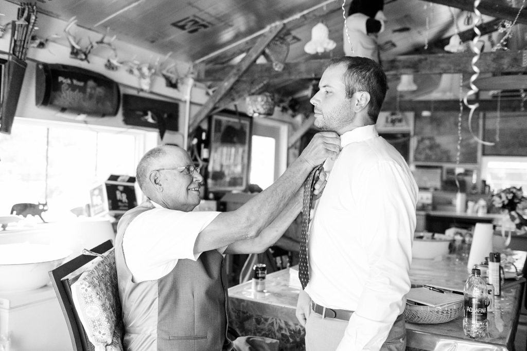 groom's father adjusting his tie at intimate childhood home wedding in Ladysmith, WI