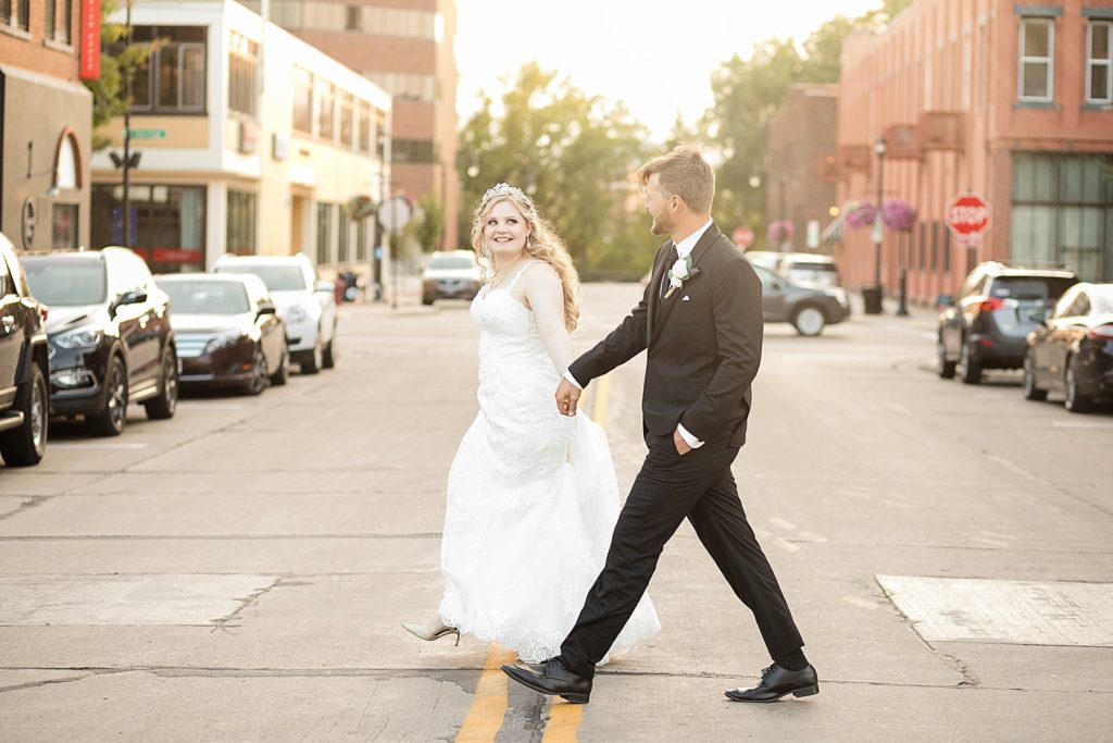 couple on their wedding day crossing the street in downtown Eau Claire