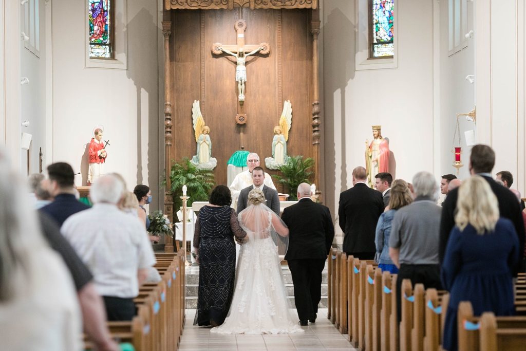 father and mother walk daughter down the aisle to her future husband at St. Charles of Borromeo in Chippewa Falls for their wedding