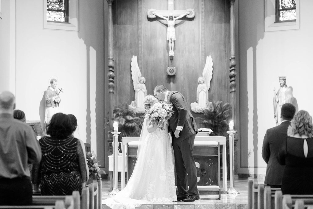 couple share their first kiss in a black and white photo at St. Charles of Borromeo in Chippewa Falls for their wedding