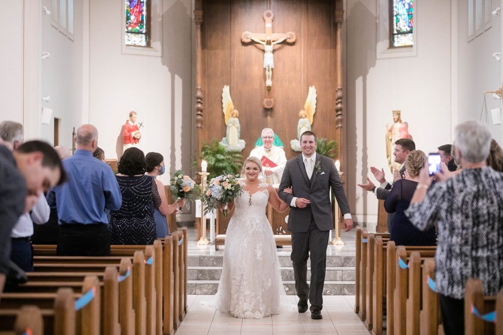 couple smiling during the recessional at St. Charles of Borromeo in Chippewa Falls for their wedding