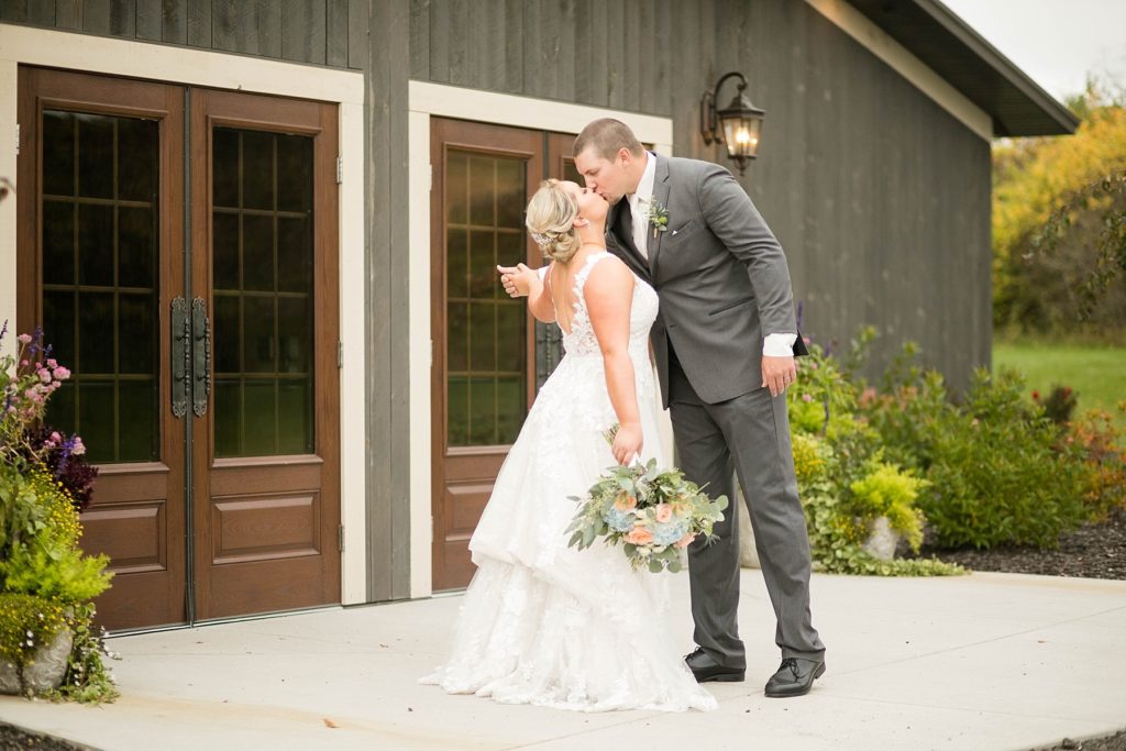 couple kiss outside the front doors at their fall wedding at Lilydale in Chippewa Falls