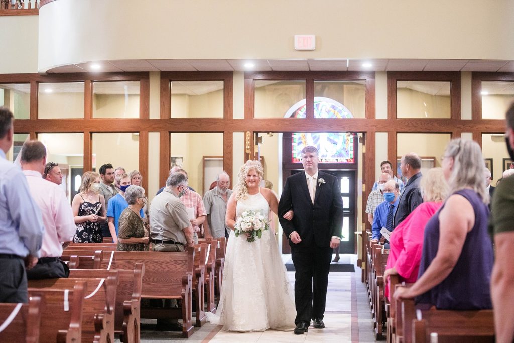 bride being walked down the aisle by her brother at Notre Dame Catholic Church in Chippewa Falls