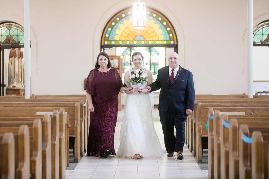 bride being walked down the aisle by her parents at St. Charles Borromeo Catholic Church in Chippewa Falls