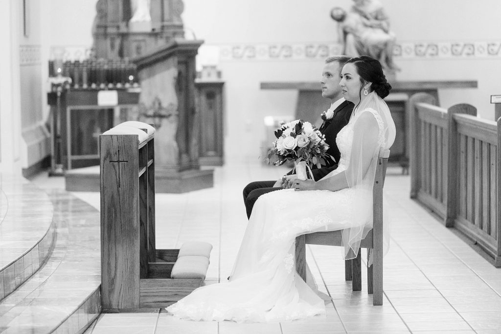 bride and groom sitting during the wedding ceremony at St. Charles Borromeo Catholic Church in Chippewa Falls