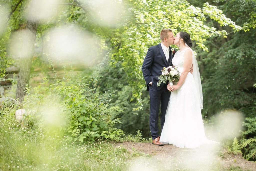 bride and groom kissing in the lush greenery  at Erickson Park in Chippewa Falls