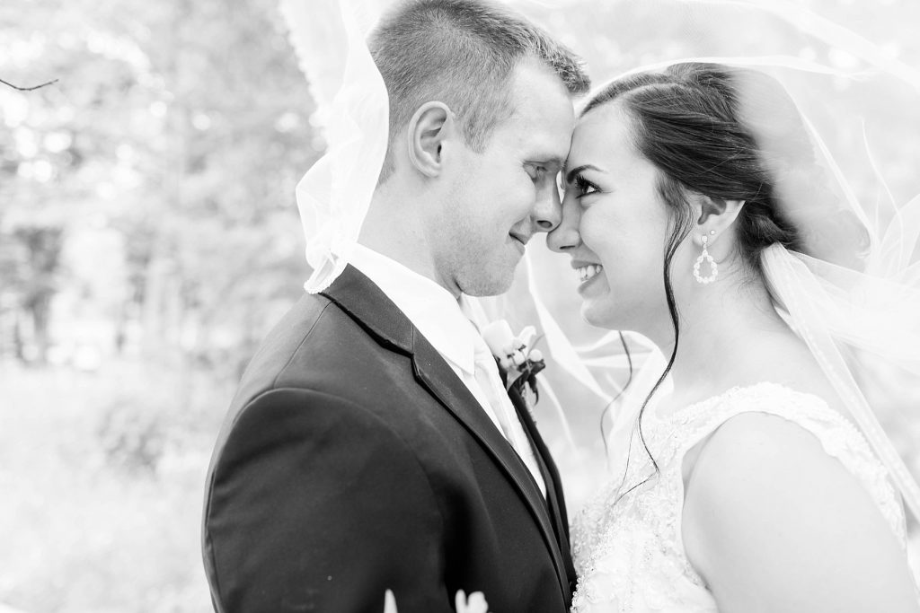 bride and groom nose to nose smiling at each other in a black and white photo  at Erickson Park in Chippewa Falls