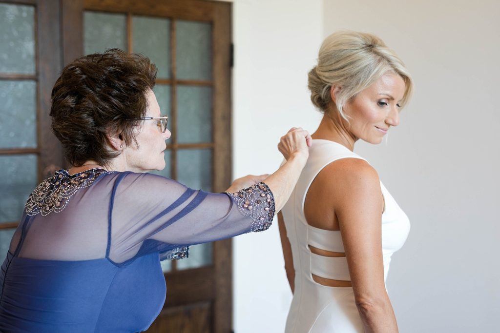 bride getting buttoned into her gown by her mom at Lilydale Dance Hall & Event Venue in Chippewa Falls