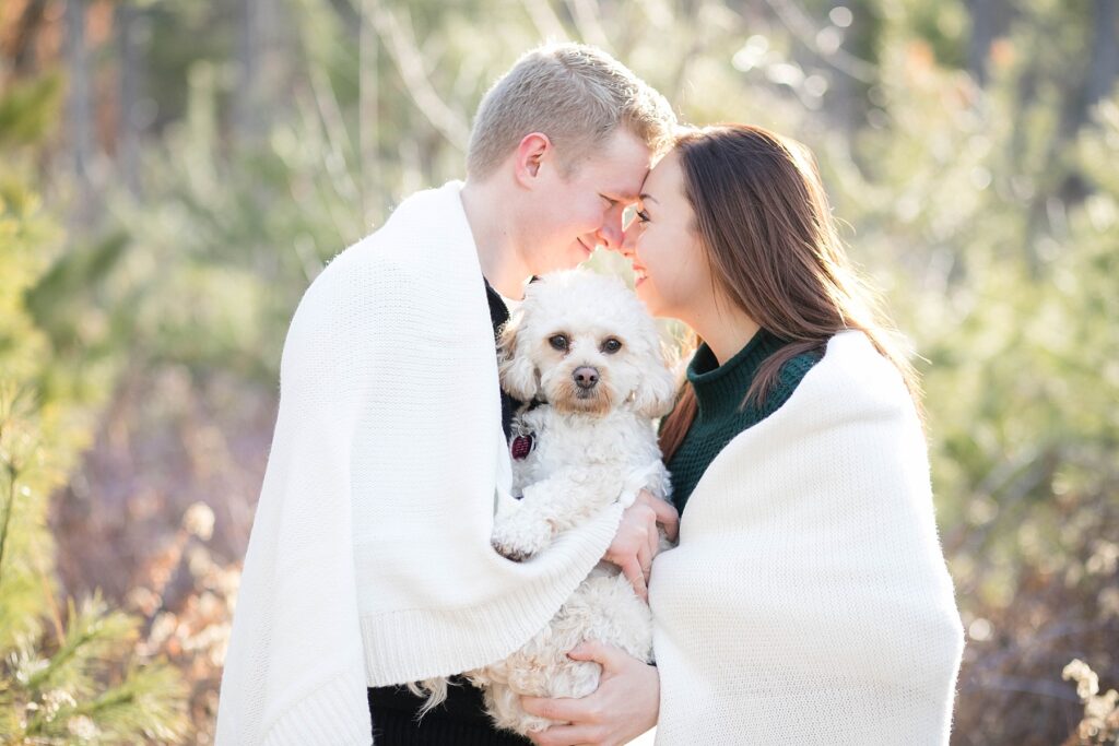 couple wrapped up in a blanket with their dog between them for an Eau Claire couple session with dog