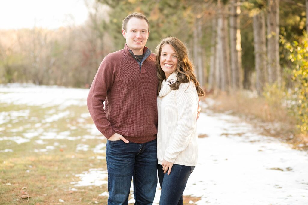 couple smiling in the snow for their Eau Claire couples session with new puppy