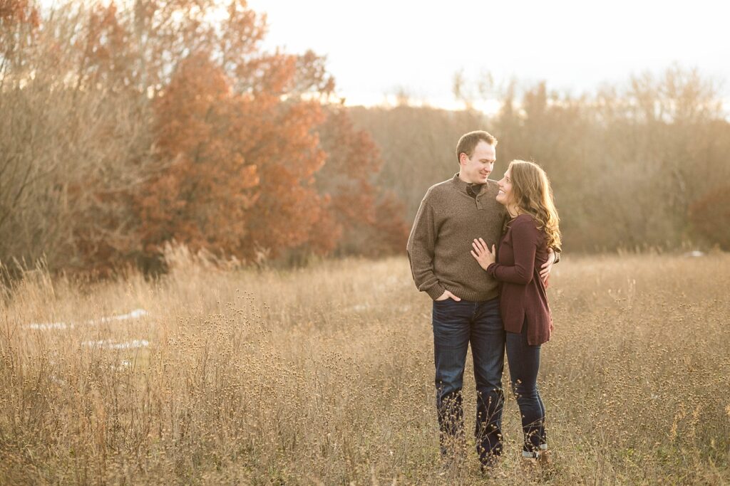 couple in a field during the fall for their Eau Claire couples session with new puppy