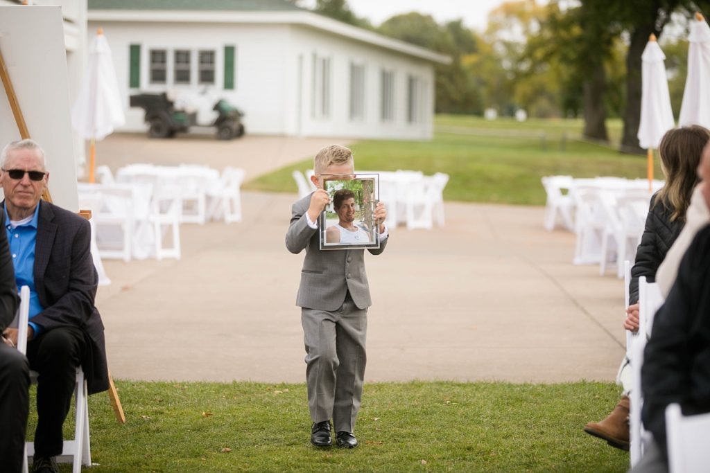 ring bearer carrying his dads photo at a wedding at Lake Wissota Golf & Events