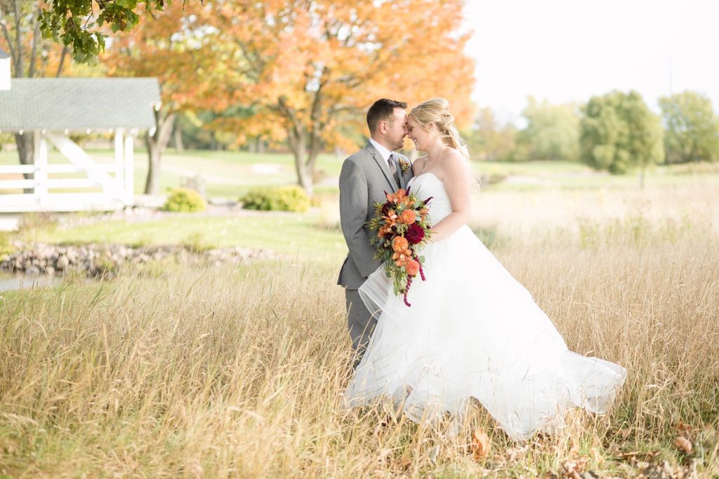 bride and groom in a field with a white bridge in the background at a wedding at Lake Wissota Golf & Events